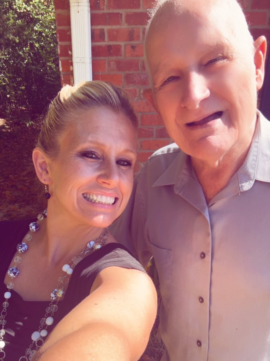 Randa smiling in a selfie with her grandfather, Papaw, outside his brick house